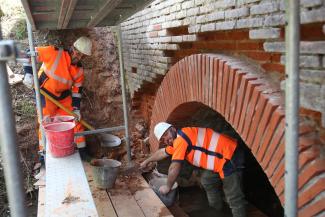 Des agents au chevet des ponts du Département Des agents du service des ouvrages d'arts en train de faire des travaux de maçonnerie sur un mur en briques
